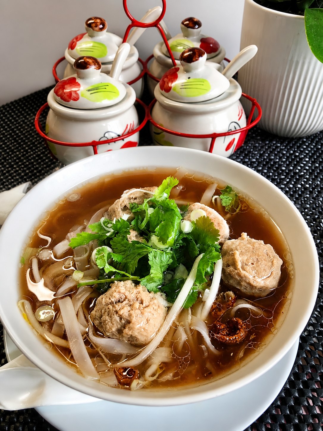 Rice noodle soup with meatballs, bean sprouts and herbs